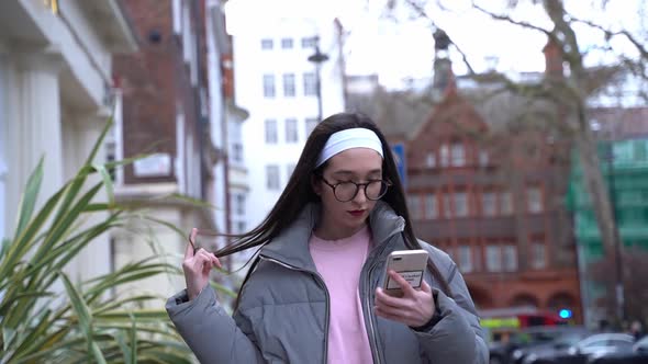 Girl walking and twirling her hair while walking down street. Slow mo.