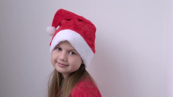Portrait of Smiling Little Girl in Christmas Santa Hat on White Background