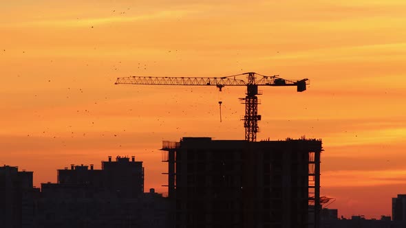 Early Morning Sky of Red and Orange Shades - Silhouettes of Buildings and Lifting Crane