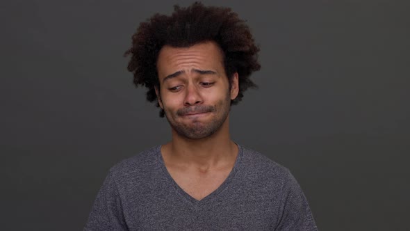 Darkskinned Man with Afro Haircut Standing with Apologetic Glance and Nodding Negatively Isolated