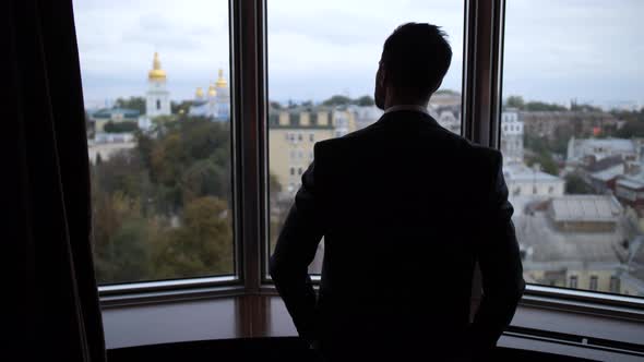 Silhoutte of Man Pulling Curtains in Hotel Room