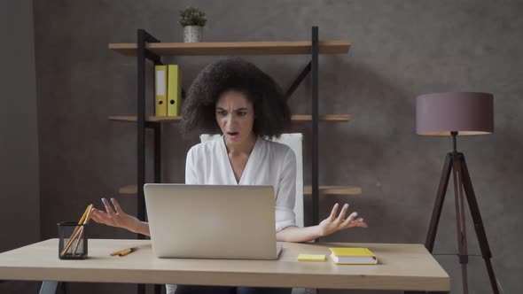 Confused Young African American Girl Sit at Desk Look at Laptop Screen, Frustrated Female Feel Mad