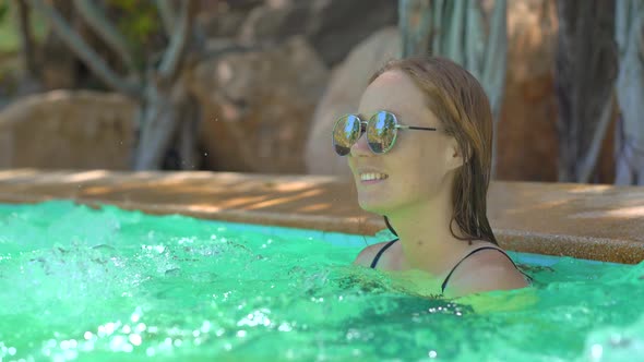 A Young Woman in a Tropical Resort with Hot Springs, Waterfalls and Swimming Pools with Hot Mineral