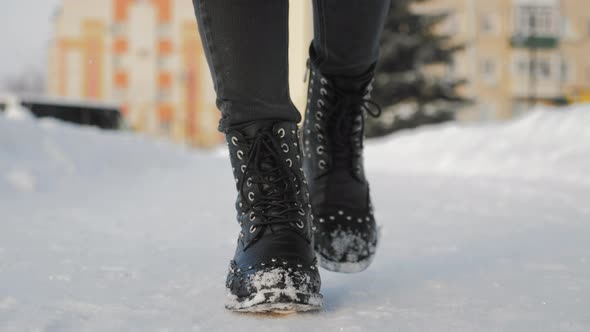 Female Feet in Black Boots Winter Walking in Snow