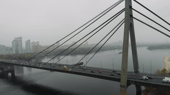 Huge concrete grey bridge with steel cables is combined two sides of metropolis in industrial smog