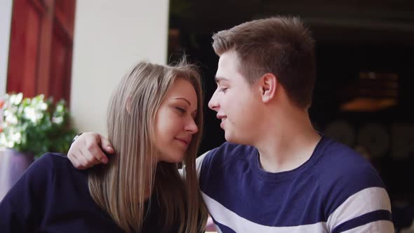 Young Couple Sitting at the Table in Cafe Embracing Each Other