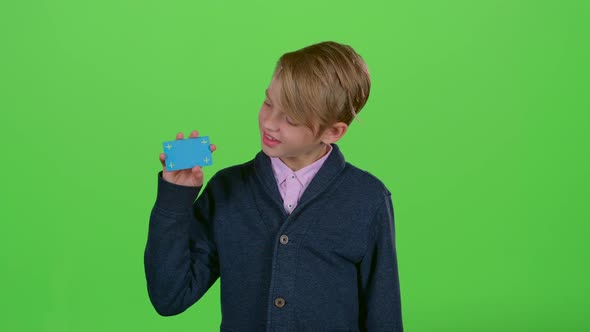 Teen Shows and Turns His Head To the Credit Card on a Green Screen