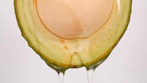 Macro Shot of Fresh Cut Avocado with Juice and Oil Stream on White Background