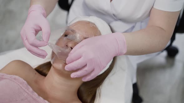 Beautician's Hands Put a Membrane on Female Face with Anesthetic Cream in Clinic
