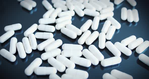 Close-up of medical pills on a black reflective surface. Approaching shot.