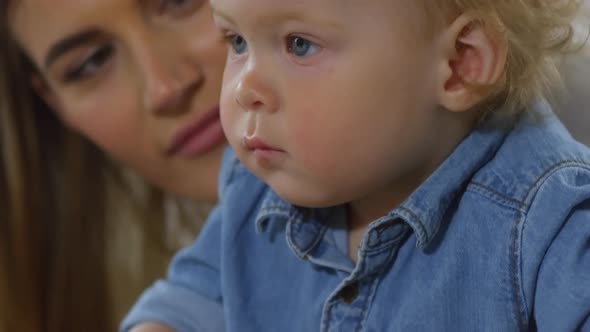 Devoted Mother Encouraging Baby to Pose