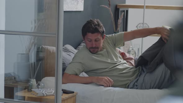 Man Using Smartphone and Leaving Bedroom after Waking Up with Wife