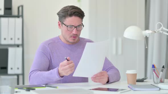 Middle Aged Man with Documents Reacting to Loss