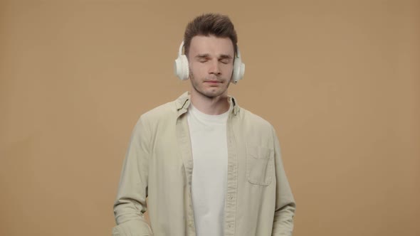 Portrait of Stylish Guy Enjoying Music in Big Wireless White Headphones