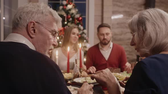 Whole Family Talking at the Table on Christmas Eve Grandma Serving the Salad