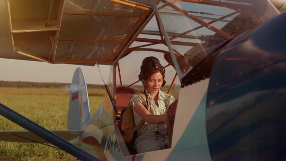 Young Adventurous Woman Pilot in Old Airplane at Summer Sunset. Freedom, Extreme and Feminism