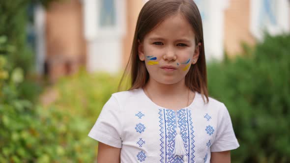 Rack Focus From Face of Pretty Ukrainian Girl in Embroidered Shirt to Raised Hand with Flag Colors