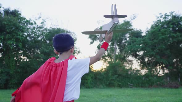 Happy Asian little boy playing airplane toy at the park