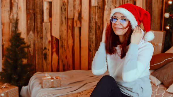 Young Woman in Santa Hat and Glasses Preening Herself in Front of Camera