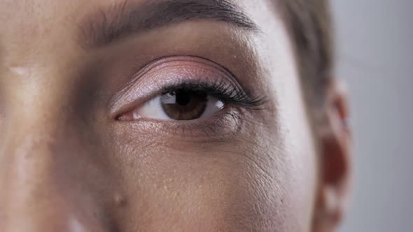 Closeup Blinking Big Brown Eye of Caucasian Female  Looking Straight at Camera Indoor Relaxed