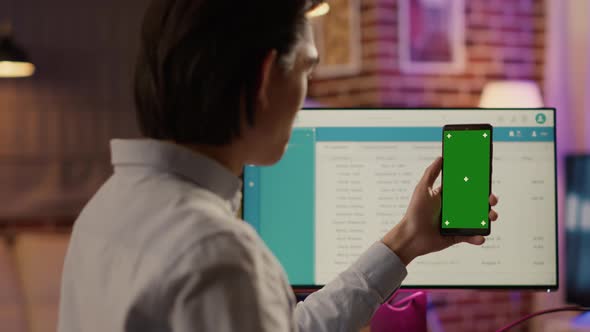 Male Freelancer Holding Smartphone with Greenscreen on Display