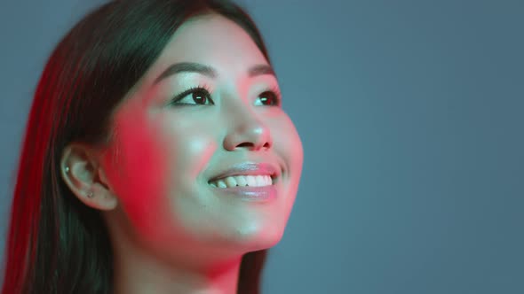 Young Pretty Asian Woman Looking at Free Space and Sincerely Smiling Expressing Inspiration Blue