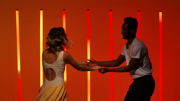 A Beautiful Sensual Couple Perform Passionate Dance Steps of Hispanics Against a Bright Red Orange