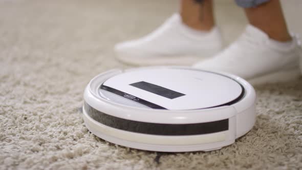 Unrecognizable Woman Turning On Robot Vacuum