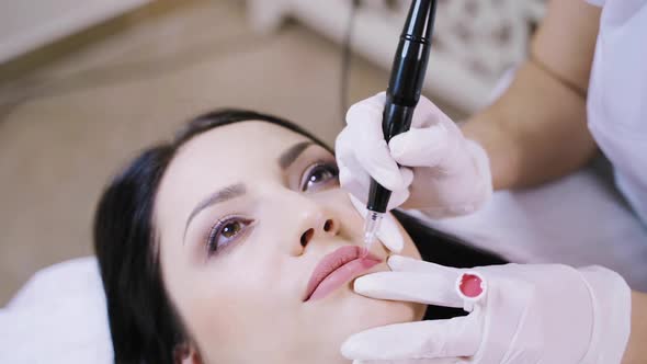 A cute brunette lying on the couch on the procedure of permanent lip makeup