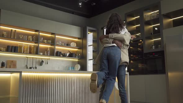 Young Woman Runs to Hug Man Partner in Modern Kitchen