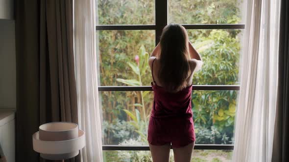 Backside View Woman in Pajama Opens Curtains in Modern Bedroom, Slow Motion