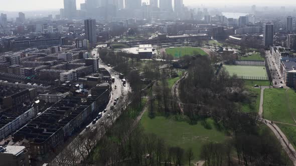 Pan up drone shot from Mile End park towards Canary wharf skyline