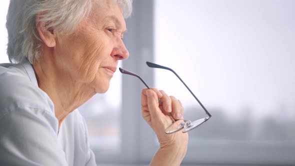 Serious senior businesswoman with short grey hair holds glasses