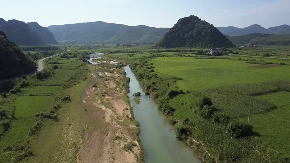 Upper View River Meanders Among Fields in Valley By Hills