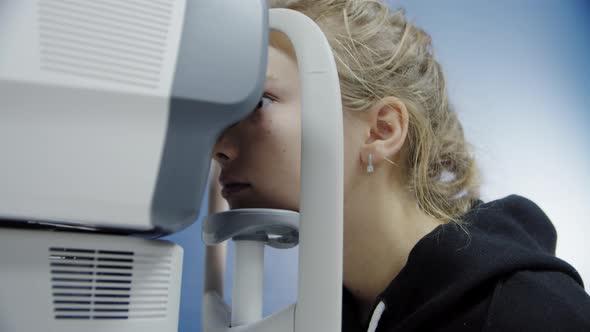 A Young Girl at an Ophthalmologist's Office Checks Her Eyesight with a Professional Device