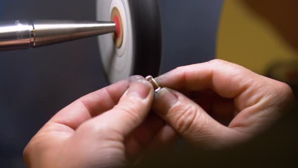 Male jewelry maker hand polishing and buffing a silver ring in a jewellery making workshop.