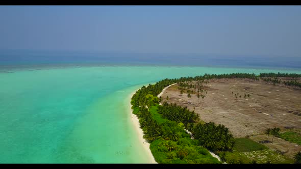 Aerial drone shot panorama of idyllic coastline beach trip by shallow ocean and white sand backgroun