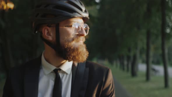 Business Man in Bike Helmet Standing in the Park at the Sunset Looking at Camera