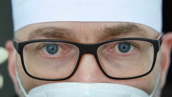 Tired Serious Mature Male Professional Doctor in Mask Eyeglasses and Protective Suite After Taking a