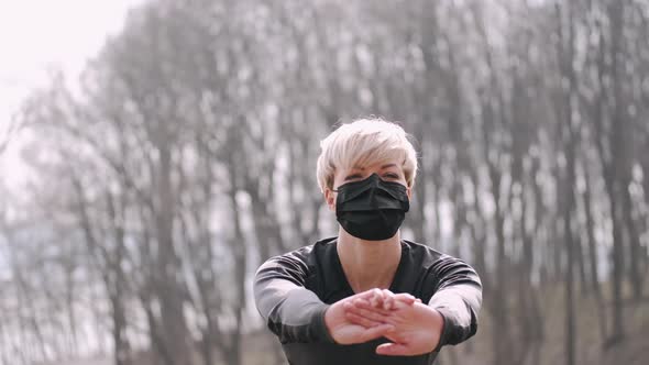 A Middle-aged Woman in a Mask Is Doing Morning Exercise Outside