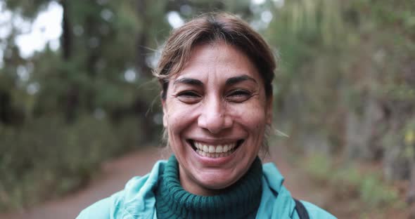 Hispanic woman smiling on camera during trekking day in to the woods
