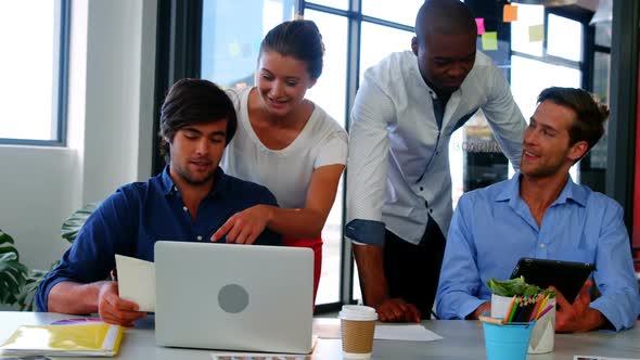 Business executives discussing over laptop and digital tablet