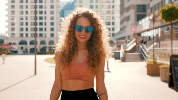 Young beautiful sexy smiling hipster woman with afro curls hairstyle posing outdoors