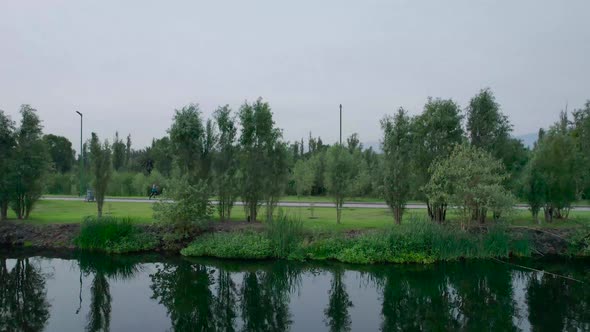 Pull-left to right above a lake, with view of a trail and a runner, in natural area in Mexico City,