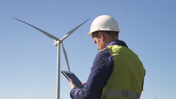 Specialist Standing Near Wind Mill and Making Inspections