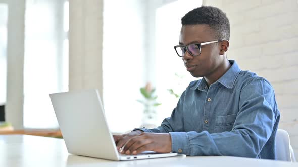 Young African Man Working on Laptop in Office