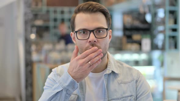 Young Man Feeling Shocked in Cafe