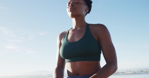 African american woman meditating at the beach on sunny day