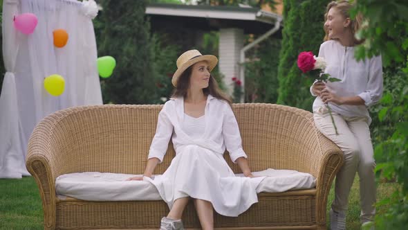 Wide Shot Portrait of Young Relaxed Caucasian Woman Sitting on Couch Outdoors As Teenage Sister