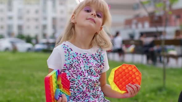Stylish Children Girl Squeezing Presses Antistress Push Pop It Popular Toy on Playground Bench